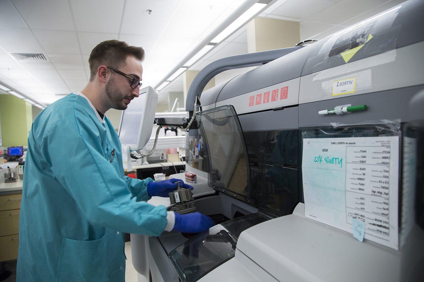 Man running medical tests in a machine in a medical lab